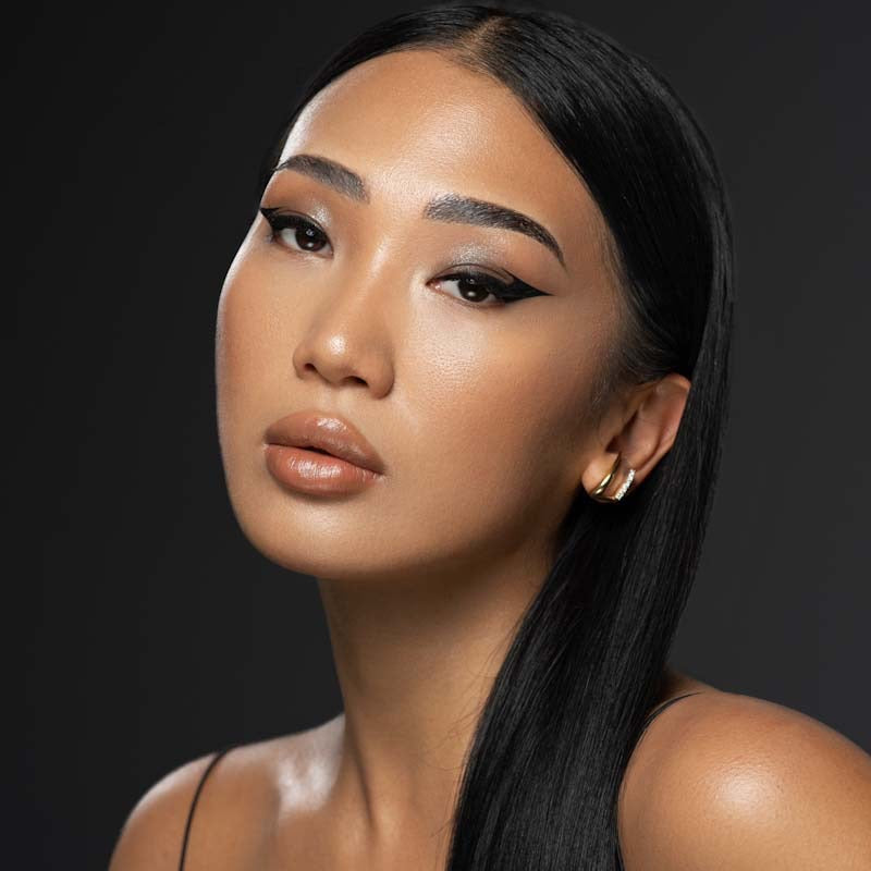 Asian woman with natural face makeup and winged eyeliner makeup staring at camera with mouth slightly parted