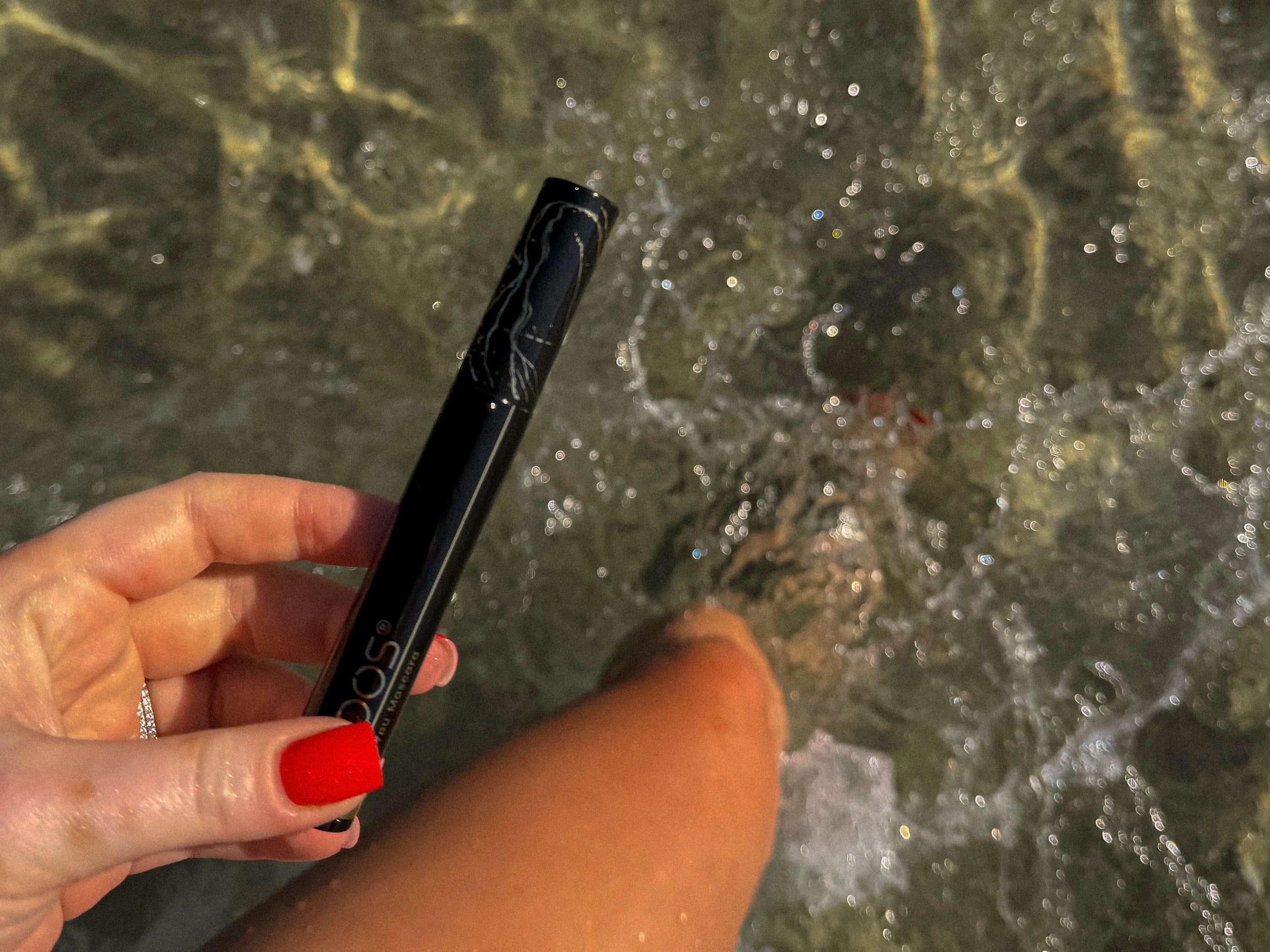 Woman applying Qudos I Wand You mascara before a day in the sun