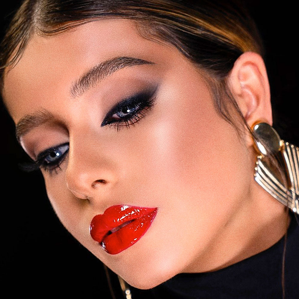 Close up of fair-skinned woman with bright red lipstick, eye makeup and natural face makeup, looking down away from camera 