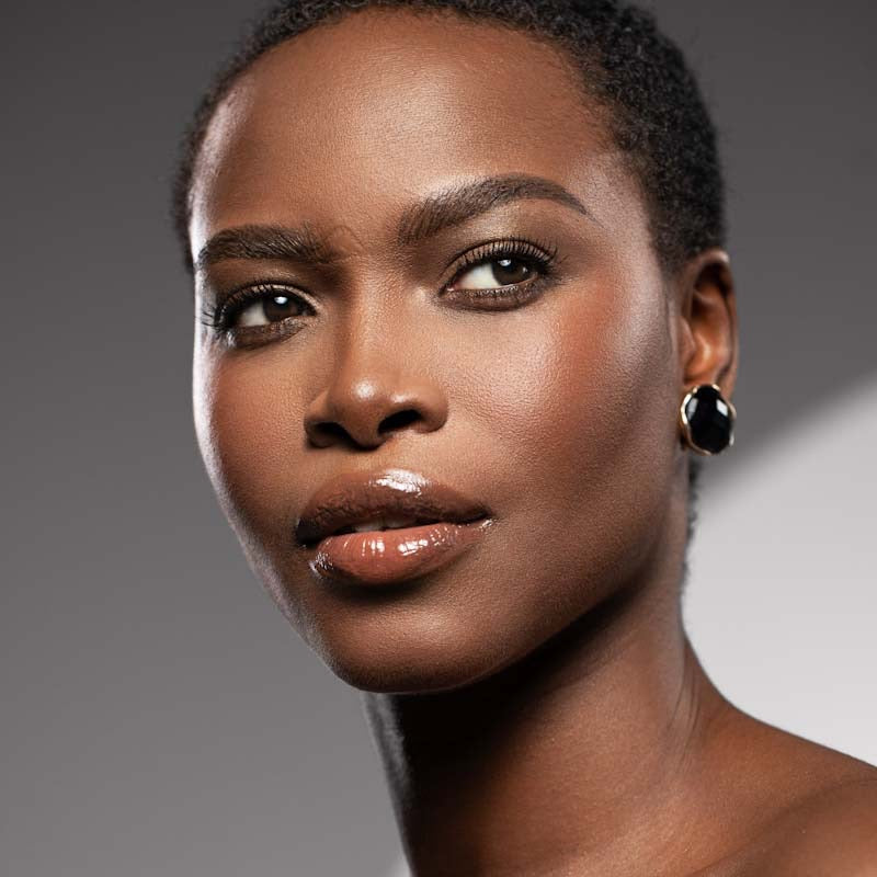 Dark-skinned woman looking away from the camera with natural face makeup and subtle eye makeup 